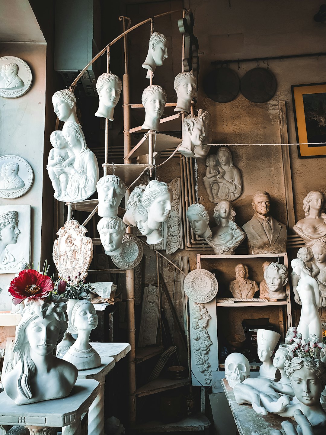 Sculture e busti in gesso riempiono lo spazio disordinato di uno studio d'artista.